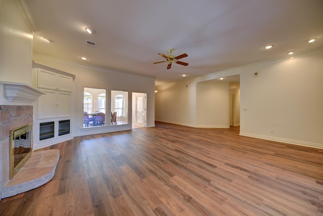 unfurnished living room featuring visible vents, a stone fireplace, crown molding, and a ceiling fan