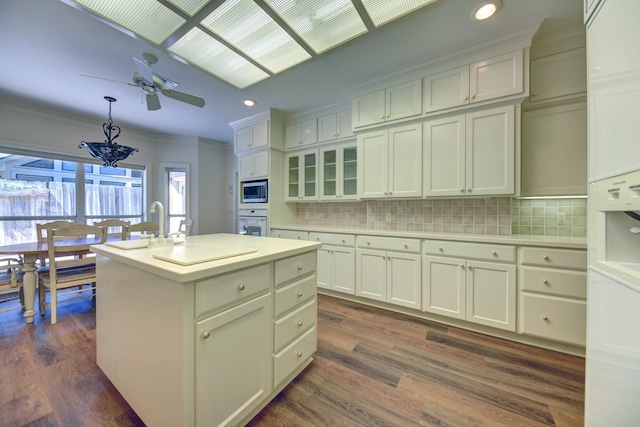 kitchen with tasteful backsplash, dark wood-style floors, light countertops, and ornamental molding