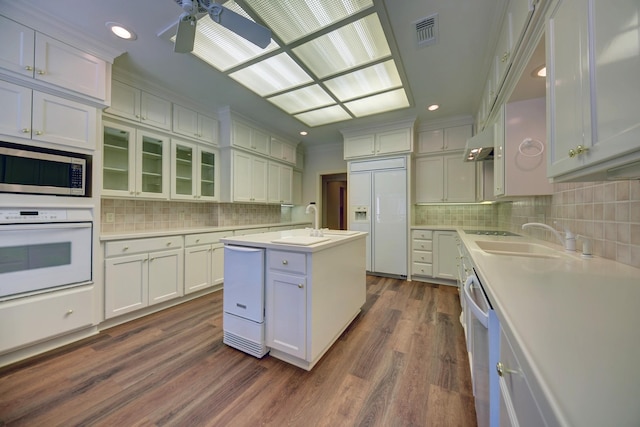 kitchen featuring built in appliances, light countertops, backsplash, visible vents, and ceiling fan