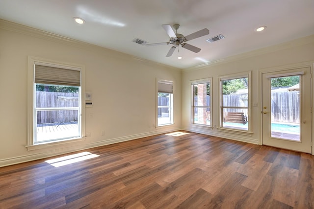 empty room featuring baseboards, ornamental molding, a ceiling fan, visible vents, and wood finished floors