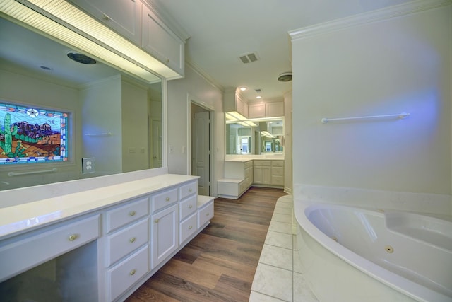 bathroom with visible vents, ornamental molding, a tub with jets, vanity, and wood finished floors