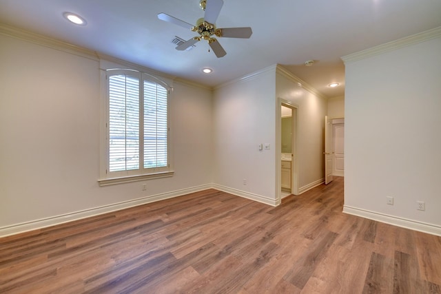 empty room featuring crown molding, wood finished floors, ceiling fan, and visible vents