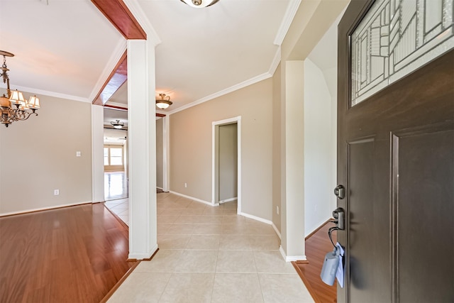 entryway featuring baseboards, ornamental molding, a chandelier, and light tile patterned floors