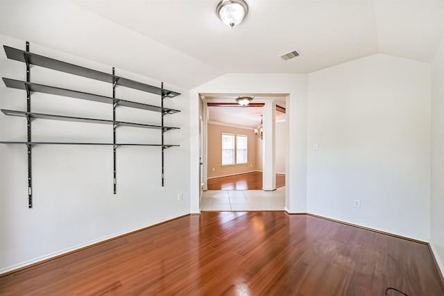 empty room featuring baseboards, visible vents, light wood-style floors, and lofted ceiling