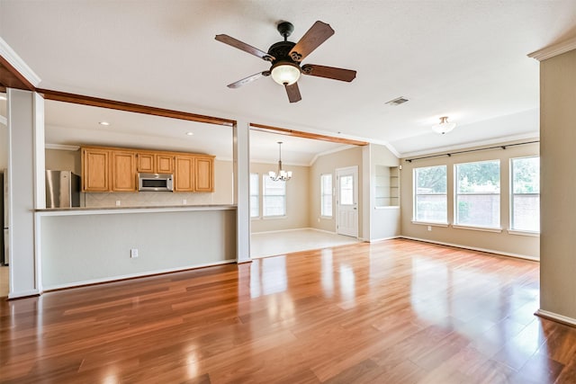unfurnished living room featuring baseboards, visible vents, ceiling fan with notable chandelier, wood finished floors, and ornamental molding