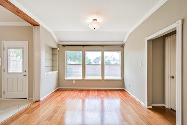 foyer with light wood finished floors, vaulted ceiling, crown molding, and baseboards