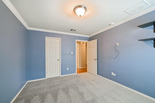 unfurnished bedroom featuring ornamental molding, visible vents, carpet flooring, and baseboards