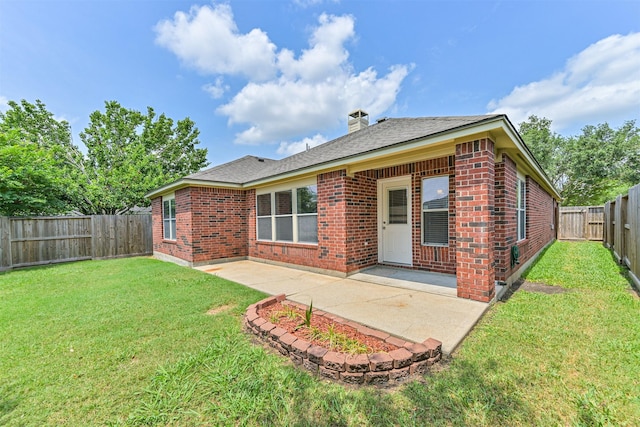 back of property with a fenced backyard, brick siding, a patio area, and a lawn