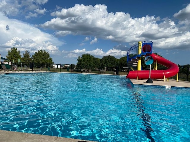 community pool with a water slide and fence