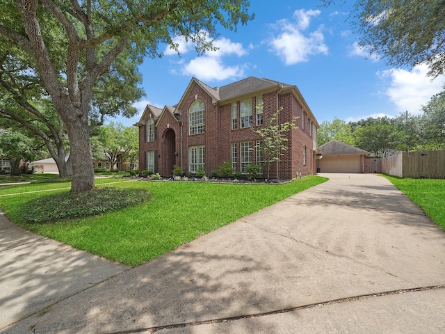 traditional-style home with brick siding, fence, a front yard, and a detached garage