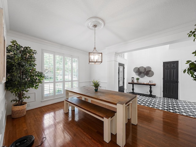 dining space with crown molding, dark wood-style flooring, and a notable chandelier