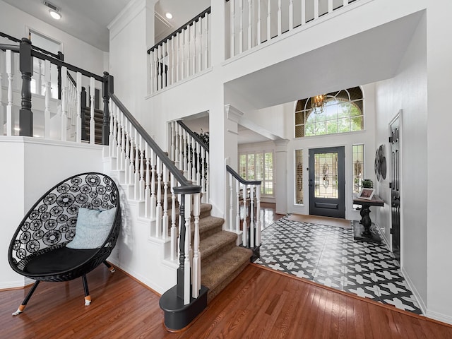 foyer featuring stairs, a high ceiling, baseboards, and wood finished floors