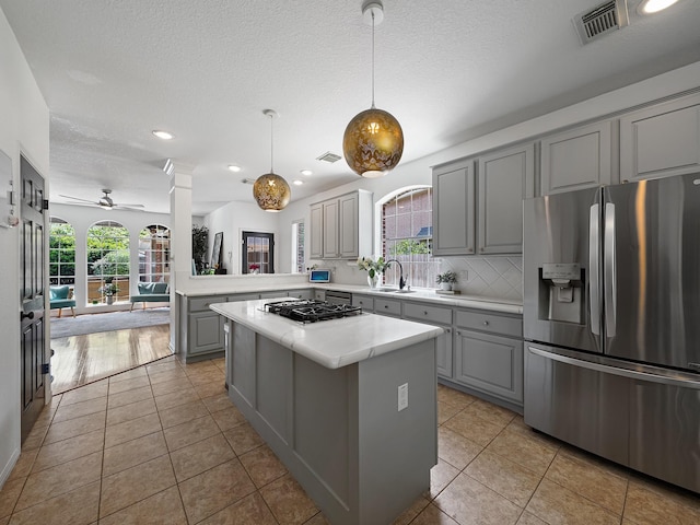 kitchen featuring light countertops, gray cabinetry, stainless steel fridge, and visible vents