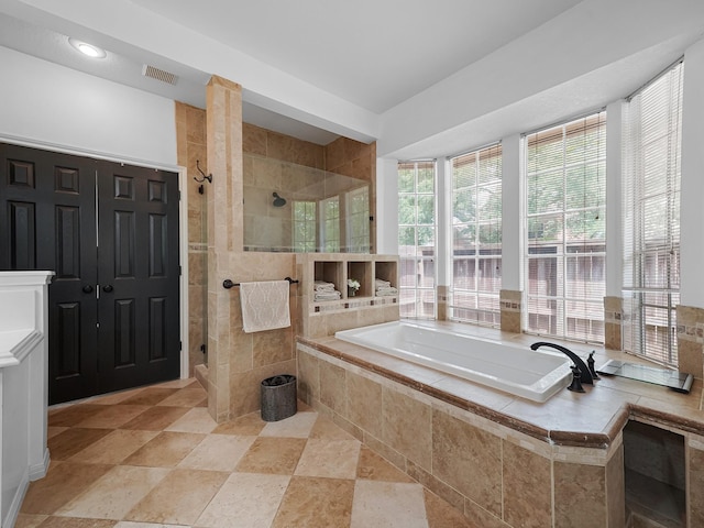 full bathroom with a stall shower, stone finish flooring, a garden tub, and visible vents