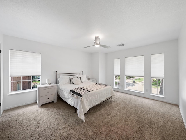 bedroom with carpet floors, ceiling fan, visible vents, and multiple windows