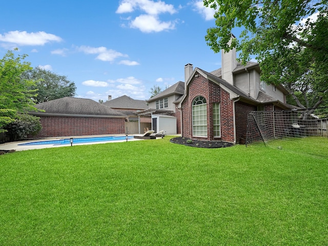 exterior space featuring fence, brick siding, a fenced in pool, a chimney, and a yard