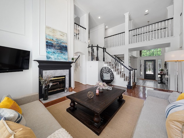 living room with stairway, a high end fireplace, a high ceiling, and wood finished floors