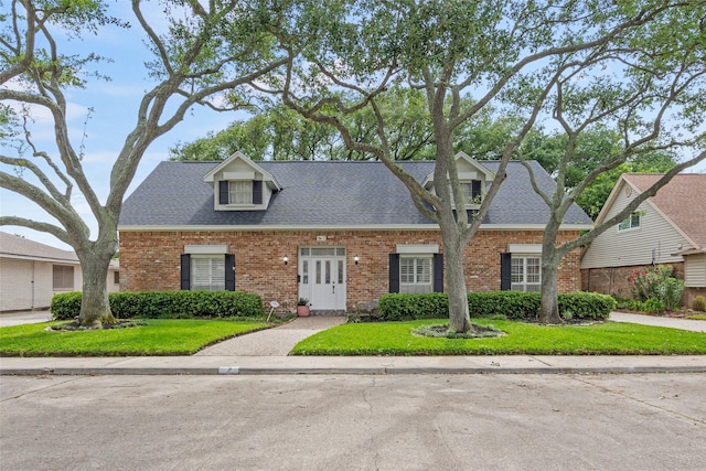 7 Colony Park Cir, Galveston, TX 77551 - cape cod-style house featuring brick siding, a shingled roof, and a front yard