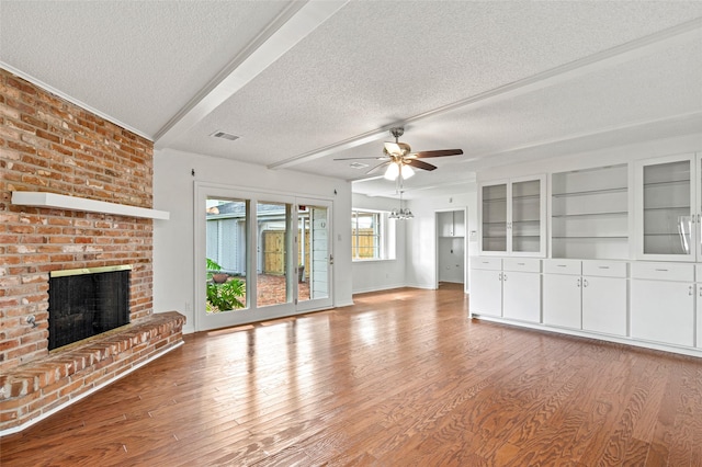 7 Colony Park Cir, Galveston, TX 77551 - unfurnished living room featuring a textured ceiling, light wood-style flooring, baseboards, a brick fireplace, and a ceiling fan