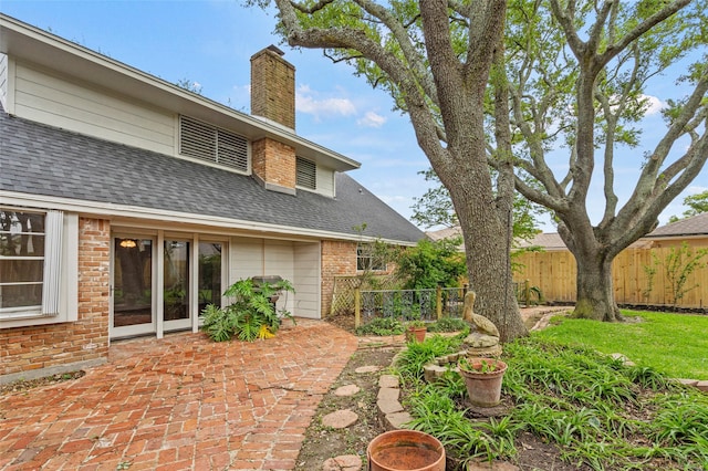 7 Colony Park Cir, Galveston, TX 77551 - rear view of property featuring a chimney, brick siding, fence, a patio, and roof with shingles
