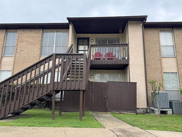 rear view of house with stairs, a balcony, and cooling unit