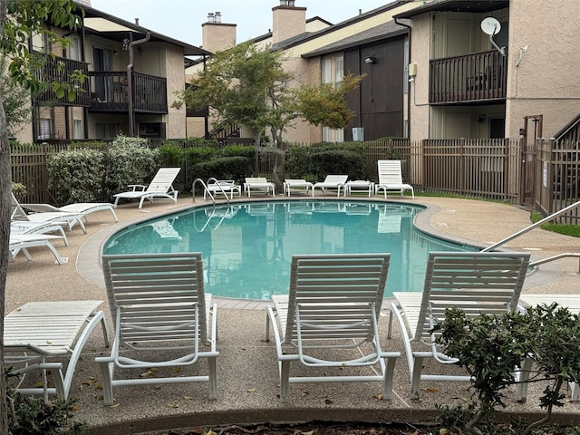 pool with a patio area and fence