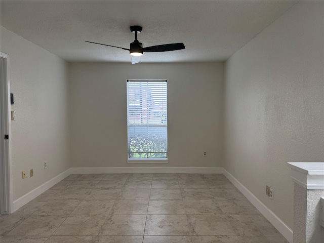 spare room with baseboards and a ceiling fan