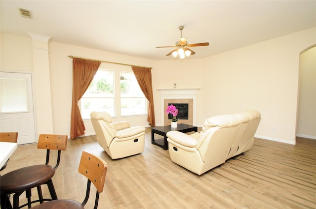 7214 Paradise Park Bnd, Richmond, TX 77407 - living area featuring light wood-type flooring, a glass covered fireplace, a ceiling fan, and visible vents