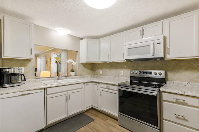 27011 Azalea Ct, Magnolia, TX 77354 - kitchen with white cabinets, a sink, a textured ceiling, tasteful backsplash, and white appliances