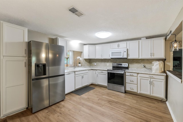 27011 Azalea Ct, Magnolia, TX 77354 - kitchen with stainless steel appliances, light wood-style flooring, and visible vents