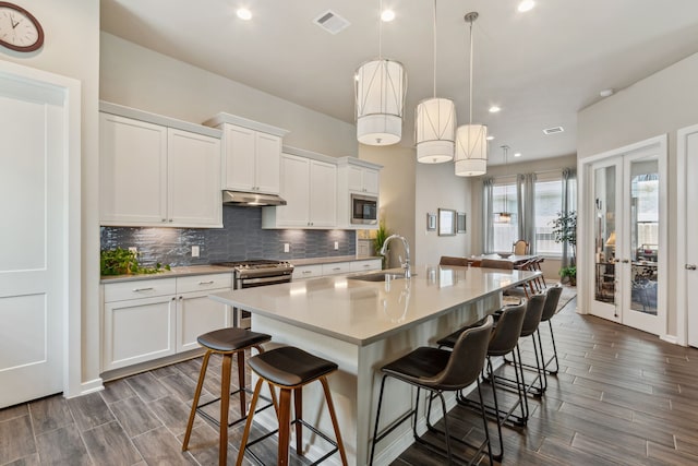 1919 Hickory Grove Ln, Tomball, TX 77375 - kitchen with tasteful backsplash, a sink, appliances with stainless steel finishes, under cabinet range hood, and a center island with sink