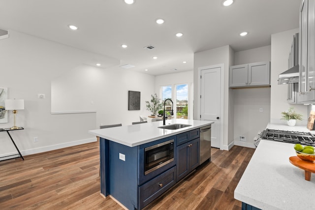 kitchen with dark wood-style flooring, a sink, light countertops, stainless steel appliances, and under cabinet range hood