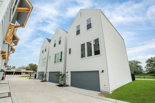 view of home's exterior with an attached garage, a yard, and driveway