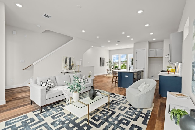 living room with visible vents, baseboards, stairway, light wood-type flooring, and recessed lighting