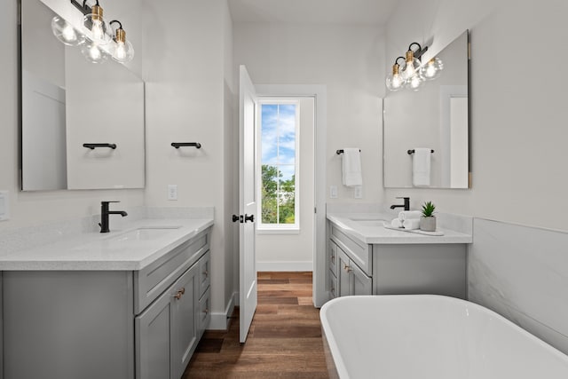 full bath with a freestanding tub, an inviting chandelier, a sink, and wood finished floors