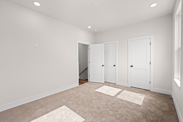 unfurnished bedroom featuring carpet floors, recessed lighting, baseboards, and two closets