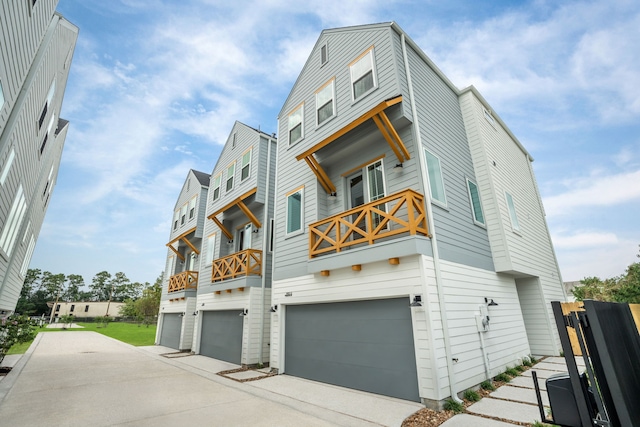 view of front facade with an attached garage, concrete driveway, and a balcony