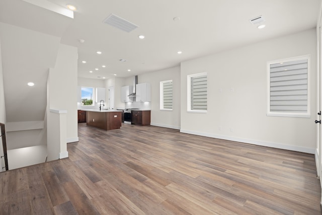 unfurnished living room featuring visible vents, recessed lighting, a sink, and wood finished floors