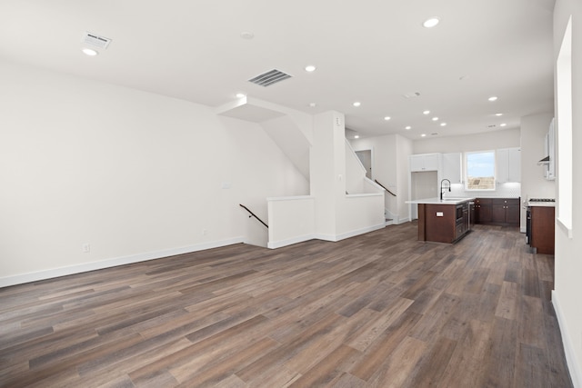 unfurnished living room with visible vents, baseboards, dark wood-type flooring, recessed lighting, and a sink