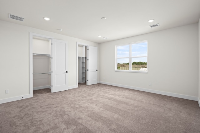 unfurnished bedroom featuring carpet floors, baseboards, recessed lighting, and visible vents
