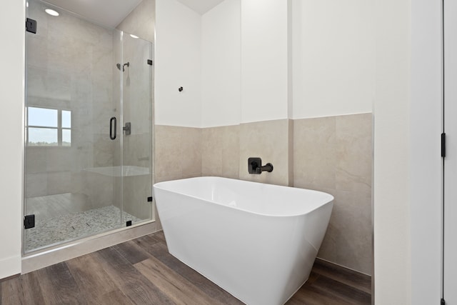 full bathroom featuring a freestanding tub, tile walls, a stall shower, and wood finished floors