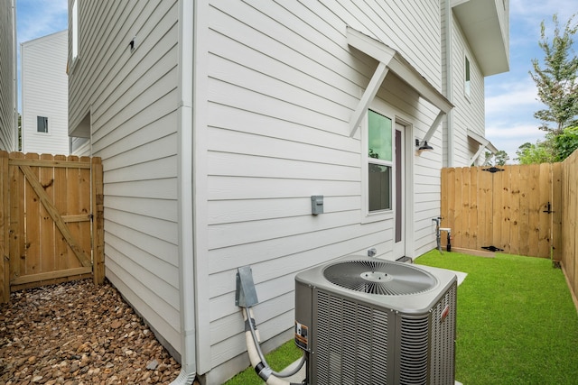 view of side of property with fence, a gate, central AC unit, and a lawn