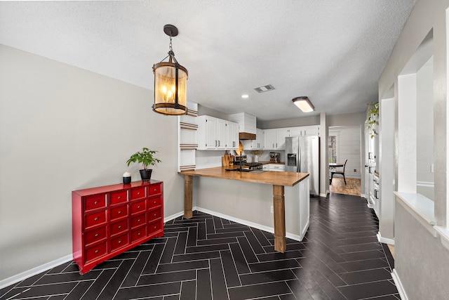 17203 Meadow Heights Dr, Houston, TX 77095 - kitchen featuring baseboards, a peninsula, white cabinets, stainless steel refrigerator with ice dispenser, and visible vents