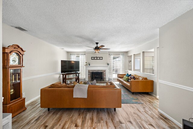 17203 Meadow Heights Dr, Houston, TX 77095 - living room featuring a fireplace, light wood-type flooring, a textured ceiling, and a ceiling fan