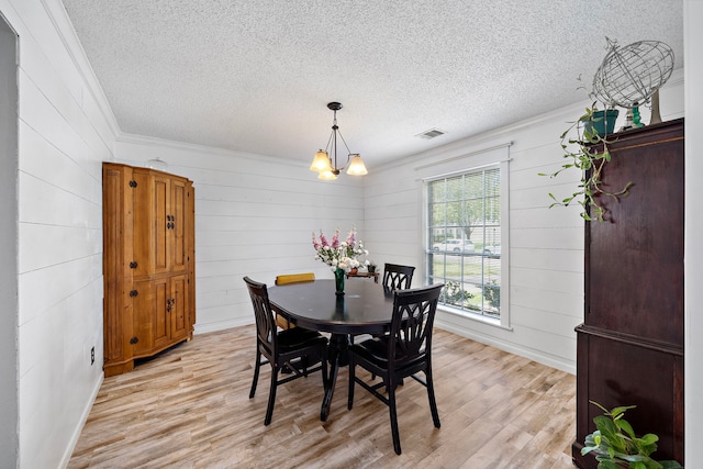 17203 Meadow Heights Dr, Houston, TX 77095 - dining space featuring light wood-type flooring, an inviting chandelier, ornamental molding, a textured ceiling, and visible vents