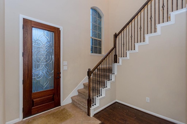 foyer entrance featuring baseboards, wood finished floors, and stairs