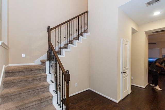 staircase with hardwood / wood-style floors, baseboards, and visible vents