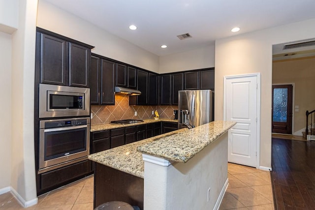 kitchen with visible vents, a sink, appliances with stainless steel finishes, under cabinet range hood, and light stone countertops