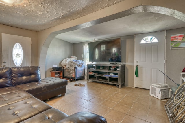 living area featuring arched walkways, a healthy amount of sunlight, and tile patterned flooring
