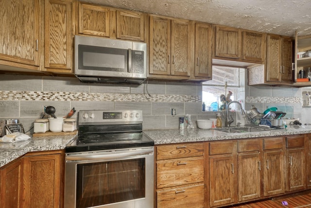kitchen with tasteful backsplash, brown cabinets, a sink, and appliances with stainless steel finishes